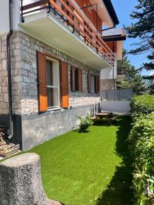 una casa con un césped verde delante de ella en Casa vacanze “La baita”, en Roccaraso