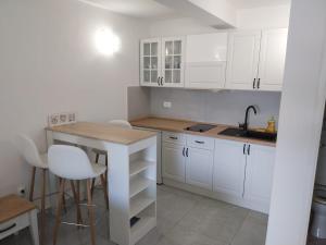 a kitchen with white cabinets and a table and a sink at Apartments Lumbarda in Lumbarda