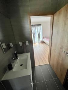 a bathroom with a white sink and a bedroom at Apartmán Roda1 Malé Lipno in Černá v Pošumaví