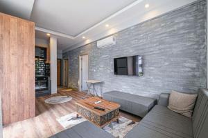 a living room with a couch and a tv on a brick wall at Palmiye Apart Hotel in Antalya
