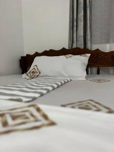 a bed with white sheets and pillows and a window at Serene Abodes in Stone Town
