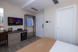 1 dormitorio con 1 cama, escritorio y TV en PATIO MARE, en Dhërmi