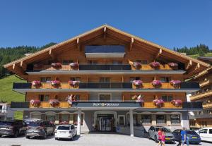 ein großes Gebäude mit davor geparkt in der Unterkunft Hotel Alpenrose in Zauchensee