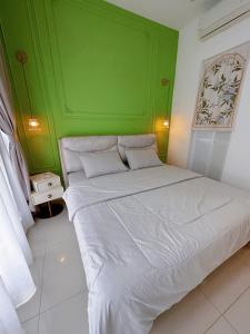 a bedroom with a green wall and a white bed at MyHomeStay@JB LEGOLAND in Nusajaya