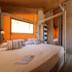 Cama grande en habitación con pared de color naranja en Devesa Gardens en El Saler