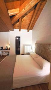 1 cama blanca grande en una habitación con techos de madera. en Cerlino's B&B, en Reggio Emilia