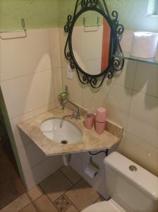 a bathroom with a sink and a mirror and a toilet at Pousada Luar do Sertão in Lençóis