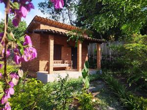 une petite maison en briques avec un banc dans un jardin dans l'établissement Pousada Luar do Sertão, à Lençóis
