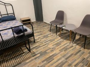 um quarto com duas cadeiras e uma cama e pisos em madeira em Ανακαινισμένος ημιυπόγειος χώρος em Lárissa