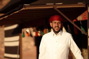 a man wearing a red hat standing under a tent at Welcome to Wadi Rum Camp in Wadi Rum