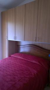 1 dormitorio con 1 cama rosa y armarios de madera en Appartamento Residence Isola Rossa, en Isola Rossa