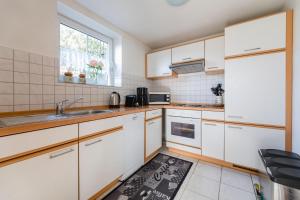 uma cozinha com armários brancos, um lavatório e uma janela em Haus Salweyblick em Niedersalwey