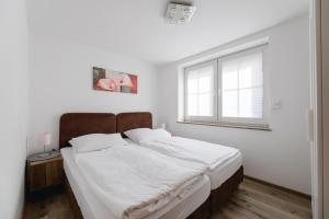 a bedroom with a bed with white sheets and a window at Haus Salweyblick in Niedersalwey