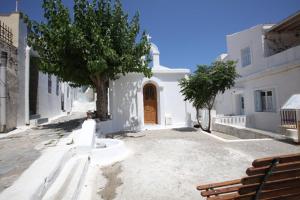 a white building with a wooden door in a street at Paraporti Room 2 in Andros