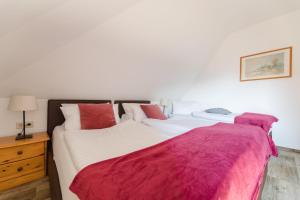 1 Schlafzimmer mit 2 Betten mit roter und weißer Bettwäsche in der Unterkunft Landhaus Salweytal in Niedersalwey