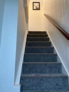 a staircase with blue carpeting and a picture on the wall at 2 Bedroom Flat Available To Let in Abbey Wood