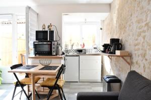 une petite cuisine avec une table et un four micro-ondes dans l'établissement La Casa De Nonna - logement classé 2 étoiles, à Rochefort