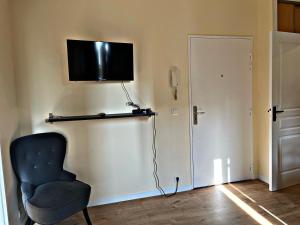 um quarto com uma cadeira e uma televisão na parede em The Garden YourHostHelper em Villejuif
