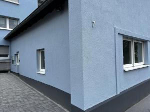 un edificio azul con dos ventanas y una acera en Business & Family - Zentral, 24h Check-In, XXL TV, en Siegburg