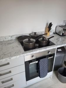 a kitchen with a stove with pots and pans on it at Lancing Apartments 2 Bedrooms, Sleeps 5 to 6 First floor Slough M4 Legoland in Slough