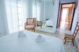 Habitación blanca con cama y espejo en Apartamento Parque Mediterráneo, en Málaga