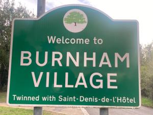 un panneau vert qui indique la bienvenue au village de bumbrian dans l'établissement Lancing Apartments 2 Bedrooms, Sleeps 5 to 6 First floor Slough M4 Legoland, à Slough