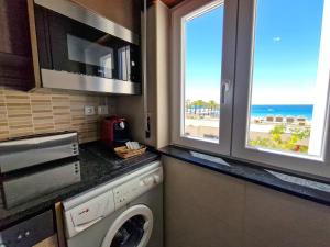 a kitchen with a washing machine and a view of the beach at Apartment Praia Rocha Vista Mar Brownie in Portimão