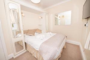 a white room with a bed with a mirror at The Seacourt in Bridlington