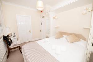 a white bedroom with a bed and a chair at The Seacourt in Bridlington
