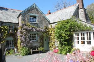 an old stone house with flowers in front of it at Culloden Farmhouse in Camelford