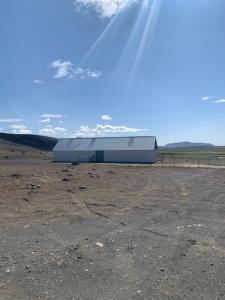 un gran edificio en un campo con cielo en Gíslaskáli en Bergsstaðir