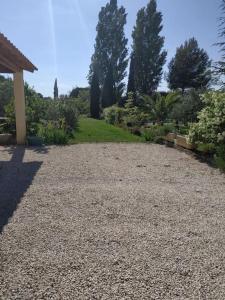 eine Kieseinfahrt in einem Garten mit Bäumen und Gras in der Unterkunft maison piscine privée Robion Luberon idéal famille in Robion en Luberon