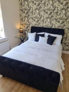a large bed with white sheets and pillows in a bedroom at Somers Lodge in Leicester