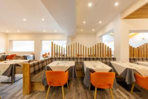 a dining room with tables and orange chairs at Active Alm Hotel in Moena