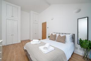 a white bedroom with a large bed with towels on it at Modern 1 Bedroom City Penthouse Apartment in London