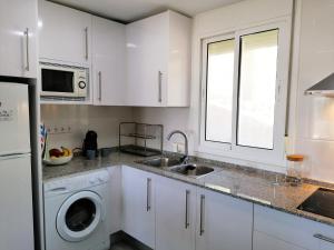 cocina blanca con fregadero y lavavajillas en AGUILA DORADA, en Salou