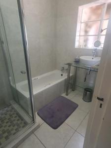 a bathroom with a shower and a tub and a sink at R & R's Retreat in Johannesburg