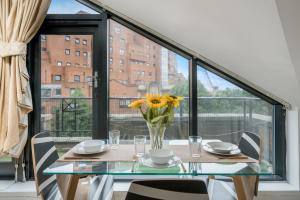 a dining room table with a vase of flowers on it at Modern 1 Bedroom City Penthouse Apartment in London