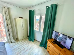 een woonkamer met groene gordijnen en een flatscreen-tv bij Ikia Village in Kyprianádes +23 foto's