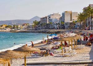 ein Strand mit Sonnenschirmen und Menschen am Strand in der Unterkunft Golden in Jávea