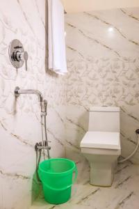 a bathroom with a toilet and a green bucket at RK GUEST HOUSE in Guwahati