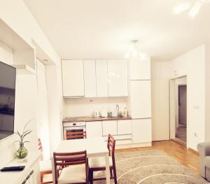 eine Küche mit weißen Schränken, einem Tisch und Stühlen in der Unterkunft Central apartment in Prilep in Prilep