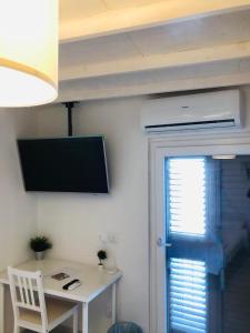 Habitación con mesa y TV en la pared. en Daiko Bed & breakfast, en Tornareccio