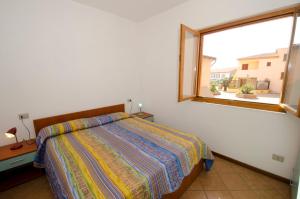 a bedroom with a bed and a large window at AIR Borgo della Torre in Isola Rossa