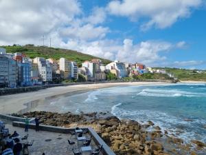 a view of a beach with buildings and the ocean at Rua as Neves in Malpica