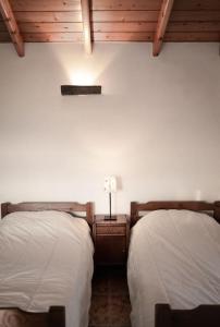 een slaapkamer met 2 bedden en een lampje aan de muur bij Abrigo dos Bodes - Goat's Shelter in Calheta