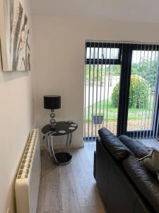 The Stables في Compton Dando: غرفة معيشة مع أريكة وطاولة مع مصباح