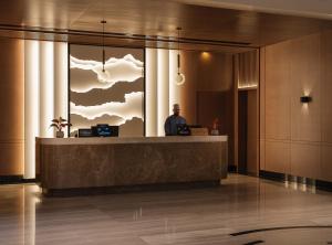 a man standing at a reception desk in a lobby at DoubleTree by Hilton Muscat Qurum in Muscat