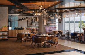 a restaurant with tables and chairs and a kitchen at DoubleTree by Hilton Muscat Qurum in Muscat