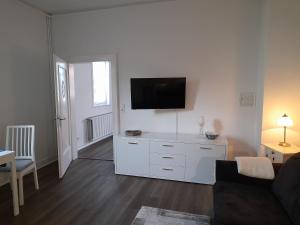 a white living room with a tv on a wall at Kleine Auszeit in Bad Fallingbostel